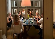 a group of women sitting around a table with bottles and glasses in front of them