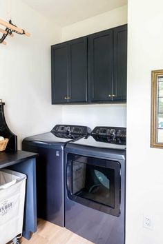 a washer and dryer in a laundry room with black cabinetry on the walls