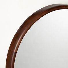 an oval mirror is shown against a white wall and has wood trim around the edge