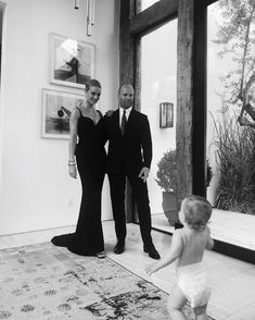 a black and white photo of a man and woman holding hands with a toddler