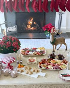 a table topped with plates and trays filled with food next to a fire place