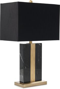 a black and gold table lamp with a black shade on the top, sitting on a white background