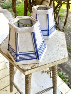 two blue and white lampshades sitting on top of an old wooden table outside