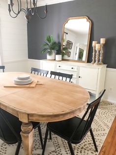 a dining room table with black chairs and a mirror on the wall in front of it