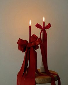 two candles with red ribbons on a stool