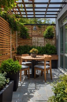 an outdoor dining area with potted plants and wooden fenced in areas around the table