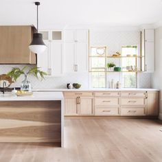 a kitchen with wooden floors and white cabinets, an island countertop and wood flooring