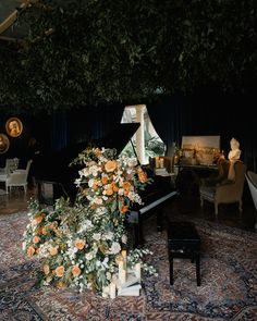 an arrangement of flowers and candles sits on the floor in front of a grand piano