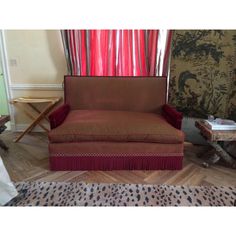 a red chair sitting in front of a window next to a cheetah rug