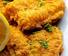 fried chicken with lemon wedges and parsley on the side