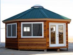 a small wooden cabin with a green roof and white doors on the front door is shown