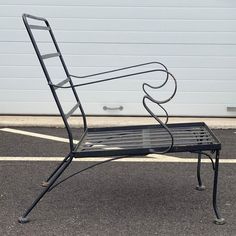 a metal bench sitting in the middle of a parking lot next to a garage door