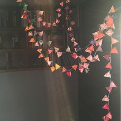 a room filled with lots of paper cranes hanging from it's ceiling next to a bookshelf