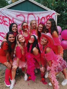 a group of young women in pink and orange outfits posing for a photo with balloons