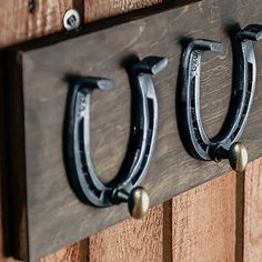 three horseshoes are mounted to the side of a wooden wall with hooks on it