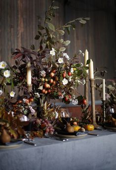 the table is set with candles, fruit and flowers