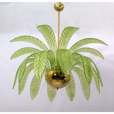 a green plant is hanging from a gold colored chandelier that has leaves on it