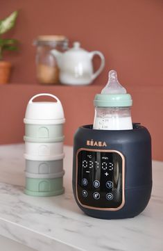 the baby bottle is sitting on top of the table next to the coffee mugs