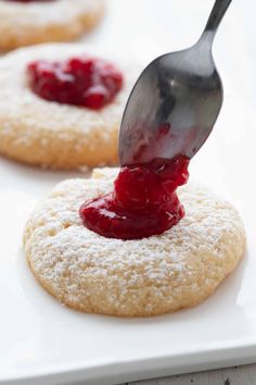 a cookie with powdered sugar and jelly on it is being drizzled with icing