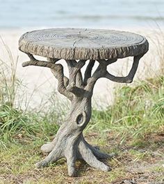 a tree stump table sitting on top of a grass covered field next to the ocean