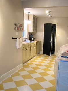 a kitchen with yellow and white checkered flooring on the walls, cabinets and counter tops