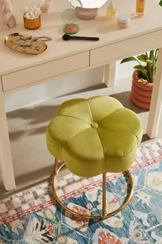 a green stool sitting in front of a white table with a mirror and other items on it