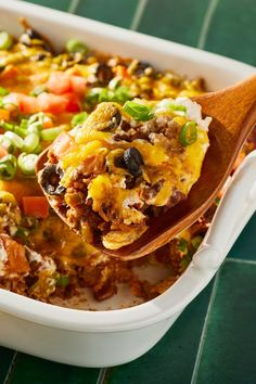 a casserole dish with tortilla shells, beans, cheese and vegetables