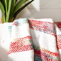 a close up of a blanket on a couch next to a potted plant