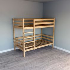 a wooden bunk bed sitting on top of a hard wood floor next to a wall