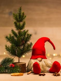 an elf doll next to a small christmas tree