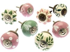 six decorative knobs with flowers and leaves painted on the front, one in pink, one in green