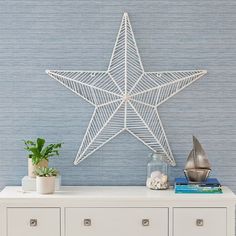 a white star on top of a dresser next to a potted plant