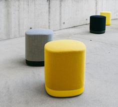 three different colored stools sitting next to each other on the cement floor in front of a concrete wall