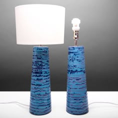 two blue vases sitting next to each other with a white lamp on top of them