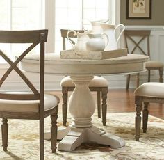 a dining room table with chairs and a vase on it's centerpiece in front of a window