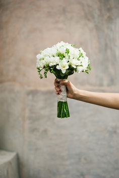 a person holding a bouquet of white flowers in their left hand and the other hand