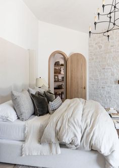 a bed with white sheets and pillows in a bedroom