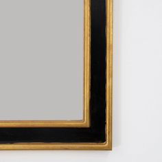 a black and gold framed mirror on a white wall