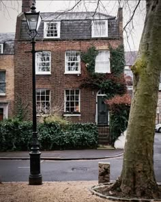 an old brick building with ivy growing on it's windows and trees in the foreground