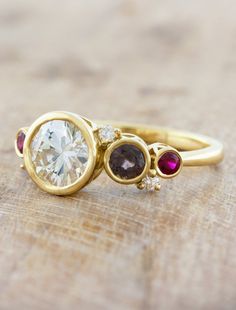 three different colored stones are on top of a yellow gold ring with white and brown diamonds