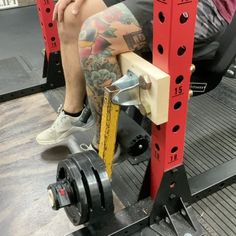 a man sitting on top of a bench next to a machine with a large tattoo on his arm