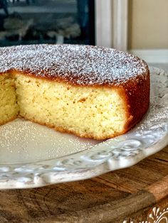 a cake on a plate with one slice cut out and powdered sugar on top