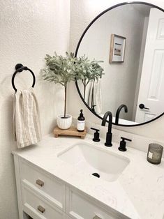 a bathroom sink with a round mirror above it and a potted plant on the counter