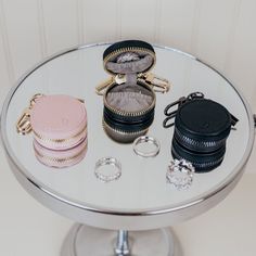 three small purses are sitting on top of a round glass table with jewelry in it