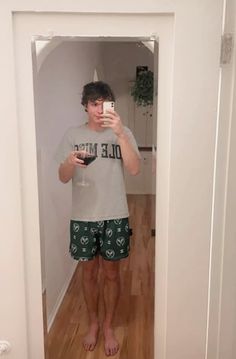 a young man taking a selfie in his pajamas while standing in front of an open door