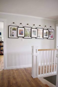 there are pictures hanging on the wall above the stairs in this room with wood flooring