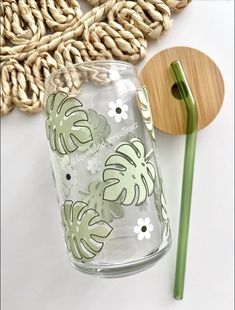 a glass cup with a green handle next to a wooden spoon and some straws