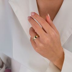 a woman's hand with a gold ring on her left wrist, wearing a white shirt