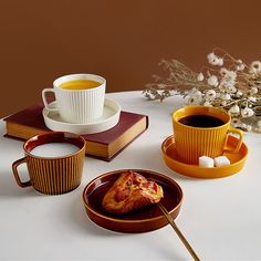 a table topped with two cups of coffee and plates filled with food next to each other