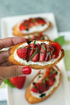 a person is holding some food in their hand and there are strawberries on top